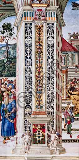 The Piccolomini Library, north-east wall: pilaster between the second scene and the third scene of the ten stories about Aeneas Sylvius Piccolomini, future Pope Pius II, (1503 - 1508), frescoes  by Bernardino di Betto, known as Pinturicchio. In the dado, the Piccolomini emblem surmounted by the papal tiara and supported by two putti.