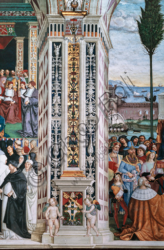 Libreria Piccolomini, parete sud-ovest: pilastro angolare tra  la nona e la decima delle dieci storie riguardanti Enea Silvio Piccolomini, futuro papa Pio II, (1503 - 1508), affreschi di Bernardino di Betto, detto il Pinturicchio. Nel dado, l’arme Piccolomini sormontata dalla tiara pontificia fra due putti reggi stemma.