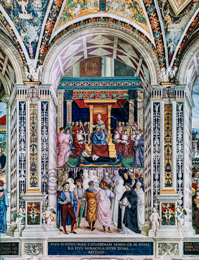 Libreria Piccolomini, parete sud-ovest: “Pio II canonizza S. Caterina da Siena, 29 giugno 1461”, la nona delle dieci storie riguardanti Enea Silvio Piccolomini, futuro papa Pio II, (1503 - 1508), affresco di Bernardino di Betto, detto il Pinturicchio.In basso a sinistra due uomini che recano ceri sono probabilmente l’autoritratto di Pinturicchio e il ritratto di Raffaello.