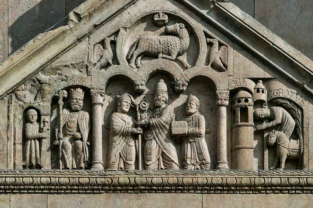 Fidenza, Duomo (St. Donnino Cathedral), Façade, the porch pediment   of the left portal.Frrom left to right: "The emperor Charlemagne, with a warrior on his right";"Pope Adrian II who hands the mitre and the croiser (symbols of episcopal dignity) to the archpriest of San Donnino"; "The miracle of the sick recovered by Domninus of Fidenza". Work by Benedetto Antelami and his workshop.