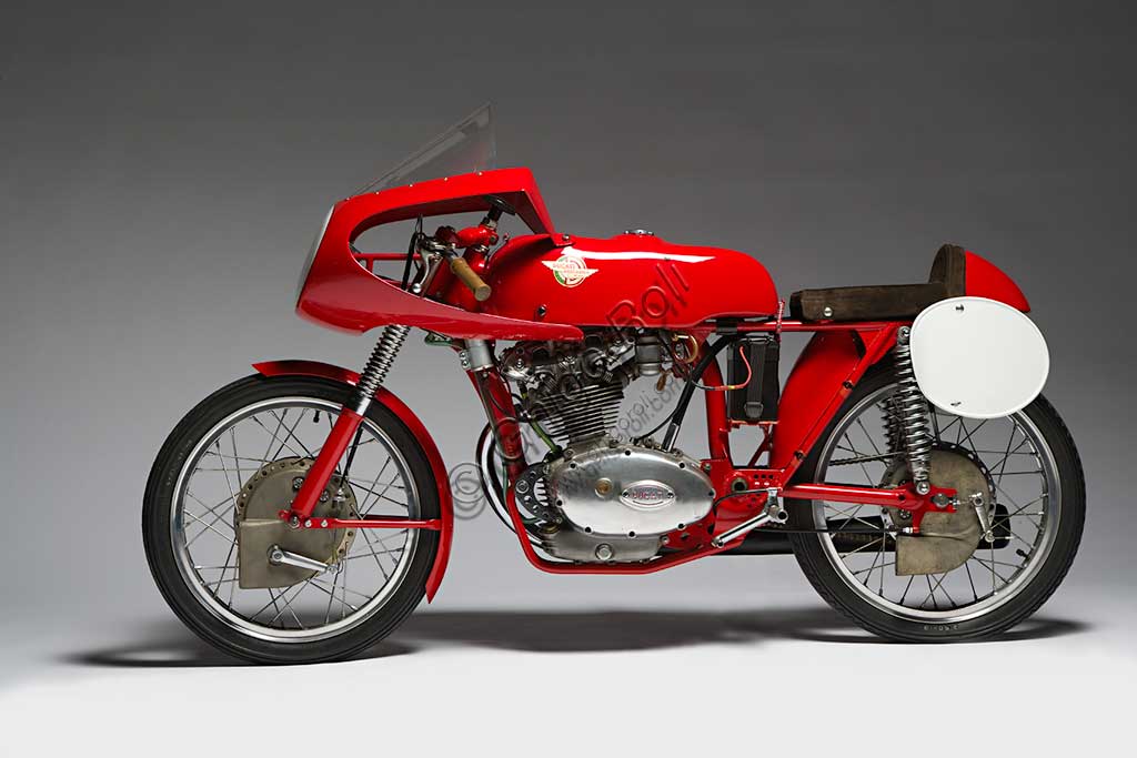 Moto d'epoca Ducati 125 Bialbero Gran PremioMarca: Ducatimodello: 125 Bialbero Gran Premionazione: Italia - Bolognaanno: 1956condizioni: restauratacilindrata: 124,8 (alesaggio e corsa 55,3 x 52)motore: monocilindricocambio: in blocco a cinque rapportiNata nel 1926 a Bologna, inizialmente la Società Scientifica Radio Brevetti Ducati si occupa di tecnologie elettromeccaniche legate alla radio fino al 1946, quando nasce il reparto motociclistico. E' di quell'anno il Cucciolo, ciclomotore a quattro tempi di grande successo. Nel '54 arriva in Ducati Fabio Taglioni, geniale ingegnere imolese che segnerà tutta la produzione Ducati per quasi quarant'anni con le sue soluzioni innovative. E' di quel periodo l'ingresso della Ducati nel mondo delle corse. Questa 125 Bialbero, moto assai rara, è l'erede diretta della 100 Gran Sport, la mitica "Marianna" che regalò le prime importanti vittorie alla Ducati, e precede di pochi mesi la 125  con distribuzione desmodromica, una soluzione che è ancor oggi il segno distintivo della produzione Ducati. 