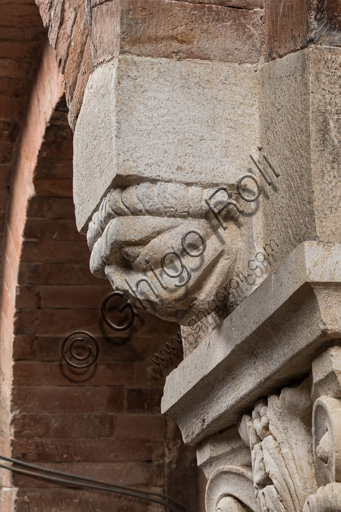 Modena, Ghirlandina Tower, Torresani Hall, east wall: a Corinthian capital with a sculpted face in the abacus protome. Campionese Masters, XII - XIII century. Detail.