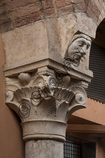 Modena, Ghirlandina Tower, Torresani Hall, north wall: a Corinthian capital with a sculpted face in the abacus protome. Campionese Masters, XII - XIII century.