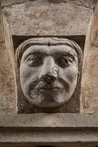 Modena, Ghirlandina Tower, Torresani Hall, north wall: a Corinthian capital with a sculpted face in the abacus protome. Campionese Masters, XII - XIII century. Detail.