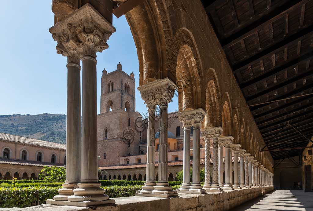 Monreale, Duomo, chiostro del monastero benedettino (XII sec.): fuga di colonne binate e capitelli nel lato Est del chiostro. Sullo sfondo, il campanile della Cattedrale.