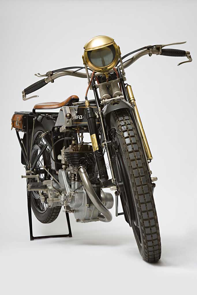 Moto d'epoca Frera SK 350 Sport. Marca: Freramodello: SK 350 Sportnazione: Italia - Milano, Tradateanno: 1925condizioni: restauratacilindrata: 348,2 cc (alesaggio e corsa 71 x 88)motore: monocilindrico a valvole lateralicambio: a tre rapportiNella produzione  Frera  i modelli SK si collocano tra i più tranquilli Turismo e i modelli SK Super Sport a valvole in testa. Vengono utilizzati anche nelle corse arrivando spesso nei primi posti. Veniva venduta normalmente senza fanale ma il tipo Sport qui illustrato, con freni anteriore e posteriore a cerchietto, monta un raro impianto di illuminazione a gas, fornito come accessorio a parte, la cui bombola è montata sullo stelo anteriore destro della forcella, mentre su quello sinistro si nota la pompa per gonfiare le gomme.