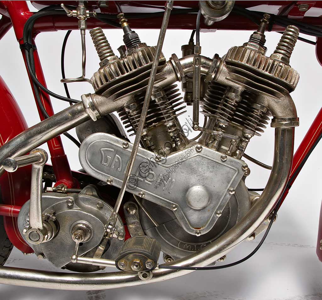 Moto d'epoca Galloni 750 SS. Motore.fabbrica: MG - Moto Gallonimodello: 750 SS fabbricata in: Italia - Borgomaneroanno di costruzione: 1920-21condizioni: restauratacilindrata: 744 cc (alesaggio e corsa: 76 x 82)motore: bicilindrico a V, a valvole lateralicambio:a mano a tre rapportiAlberto Galloni, titolare della MG di Borgomanero, costruisce la sua prima moto da corsa nel 1919. In sella a questa bicilindrica il pilota Miro Maffeis si aggiudica alcuni record mondiali. L'anno successivo inizia la produzione di serie con una due tempi ed una 500 quattro tempi bicilindrica. La fabbrica rimarrà attiva fino al 1932, creando una decina di modelli, alcuni dei quali  raccolsero diversi successi in campo sportivo con i piloti Augusto Rava e Alfredo Panella. L'esemplare qui mostrato divide con un'altra moto simile di 500 cc, l'onore di essere l'unica superstite nota di tutta la produzione. Elegante nelle forme e nelle soluzioni tecniche, ha cilindri e teste nichelati, tappi delle teste interamente alettati, serbatoio a due scomparti con dosatore regolabile, forcella elastica brevettata a due molle in compressione. Monta un freno a tamburo sulla ruota posteriore.