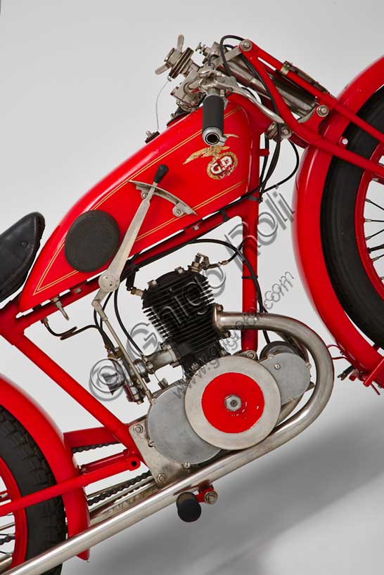 Moto d'epoca “G.D. CM Turismo 175”Marca: G.D. - Fabbrica Italiana Motocicli Ghirardi & Dall'Oliomodello: CM Turismo 175nazione: Italia - Bolognaanno: 1928condizioni: restauratacilindrata: 175motore: due tempi, monocilindrico, a doppio tubo di scarico cambio: in semiblocco a tre marceLa G.D. fu fondata a Bologna nel 1923 e, fin dalla nascita, fu molto attenta alla attività agonistica. Già il suo primo modello, una bici a motore di 123 cc, nel primo anno di vita vinse 18 gare sulle 22 alle quali partecipò. Nel 1924 Ildebrando Cavedagni, realizzatore del telaio, batté il record del chilometro lanciato. Anche negli anni successivi molte delle numerose vittorie furono firmate da meccanici e progettisti dipendenti dell'azienda (Sceti e Drusiani, oltre a Cavedagni) che si trasformavano all'occorrenza in piloti, testimoniando sia la grande passione personale, che lo spirito pionieristico del motociclismo in quell'epoca.  Questo rarissimo esemplare presenta: doppie luci di ammissione con condotto di aspirazione sdoppiato, doppie luci di scarico con due tubi. Forcella elastica speciale con ammortizzatori a glicerina.