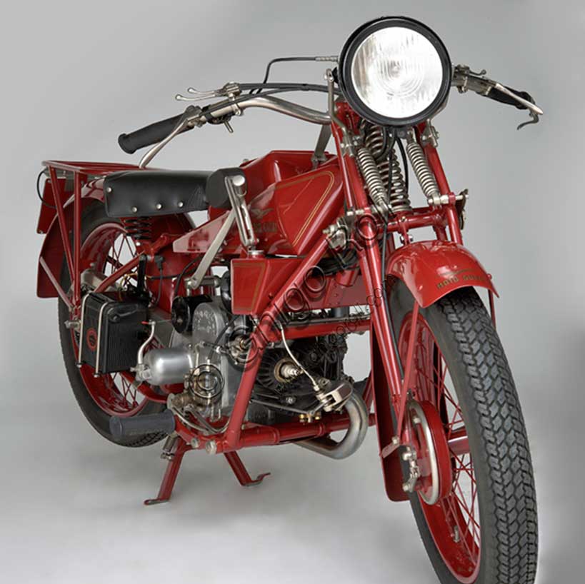 Moto d'epoca “Guzzi Sport 14”Marca: Moto Guzzimodello: Sport 14nazione: Italia - Mandello Larioanno: 1929condizioni: restauratacilindrata: 498,4 cc (Alesaggio e corsa 88 x 82)motore: quattro tempi monocilindrico orizzontalecambio: in blocco a tre rapportiLa Sport 14, ultima Guzzi con serbatoio "sottocanna", si colloca come modello di transizione tra la prima Tipo Normale e i modelli di grande successo degli anni trenta. Nonostante il nome Sport, nasce come modello prevalentemente votato al turismo e si rivolge a quel pubblico ormai affezionato alla casa, che cerca moto robuste e affidabili da usare ogni giorno e anche nei viaggi più impegnativi. Una rapida occhiata ai comandi è sufficiente per capire cosa significasse guidare le moto degli anni '20: al manubrio troviamo le tre manette di gas, aria e anticipo, le tre leve di frizione, alzavalvole e freno anteriore, il pomello del frenasterzo;  al lato del serbatoio la leva del cambio, poi i pedali del freno posteriore, il rubinetto dell'olio, il rubinetto della benzina e il cicchetto, oltre naturalmente a tutti i comandi elettrici.