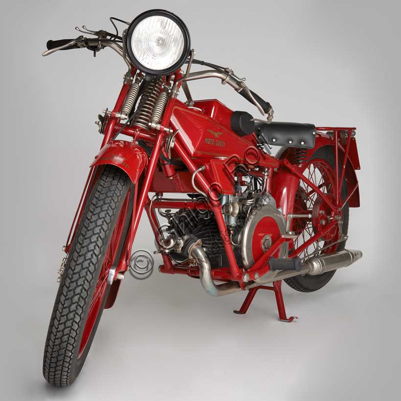 Moto d'epoca “Guzzi Sport 14”Marca: Moto Guzzimodello: Sport 14nazione: Italia - Mandello Larioanno: 1929condizioni: restauratacilindrata: 498,4 cc (Alesaggio e corsa 88 x 82)motore: quattro tempi monocilindrico orizzontalecambio: in blocco a tre rapportiLa Sport 14, ultima Guzzi con serbatoio "sottocanna", si colloca come modello di transizione tra la prima Tipo Normale e i modelli di grande successo degli anni trenta. Nonostante il nome Sport, nasce come modello prevalentemente votato al turismo e si rivolge a quel pubblico ormai affezionato alla casa, che cerca moto robuste e affidabili da usare ogni giorno e anche nei viaggi più impegnativi. Una rapida occhiata ai comandi è sufficiente per capire cosa significasse guidare le moto degli anni '20: al manubrio troviamo le tre manette di gas, aria e anticipo, le tre leve di frizione, alzavalvole e freno anteriore, il pomello del frenasterzo;  al lato del serbatoio la leva del cambio, poi i pedali del freno posteriore, il rubinetto dell'olio, il rubinetto della benzina e il cicchetto, oltre naturalmente a tutti i comandi elettrici.
