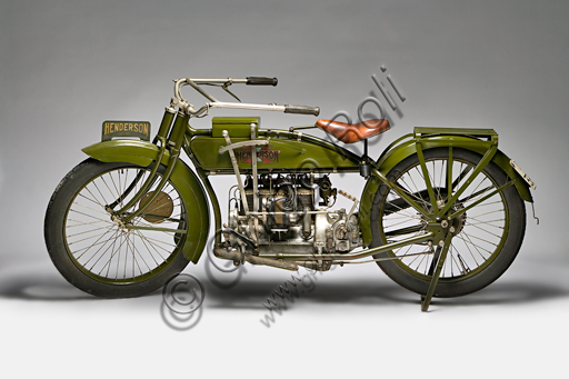 Moto d'epoca Henderson 1100 mod G.Marca: Henderson & Supply Co.modello: 1100 mod Gnazione: U.S.A. - Detroit / Chicagoanno: 1917condizioni: restauratacilindrata: 1068 (alesaggio e corsa motore: quattro cilindri in linea a valvole contrappostecambio: Il marchio Henderson è legato indissolubilmente al quattro cilindri più noto e amato degli U.S.A. Purtroppo, a causa di difficoltà economiche, la Henderson sarà acquisita già nel '17 dalla Excelsior che trasferirà gli stabilimenti a Chicago. Fu a bordo di una Henderson quattro cilindri che Carl Stearns Clancy di New York fece per primo il giro del mondo in moto (era il 1913 e questo la dice lunga sull'affidabilità di questa moto...). Caratteristiche particolari:  Ha forcella anteriore a ruota tirata, con biscottini inferiori e molle racchiusi in astucci tubolari. Ha valvole contrapposte con aspirazione in testa e scarico laterali, comandate da un unico asse a cammes sulla destra del basamento.Questo esemplare è la prima moto storica iscritta all'ASI e porta il numero di iscrizione 0001.