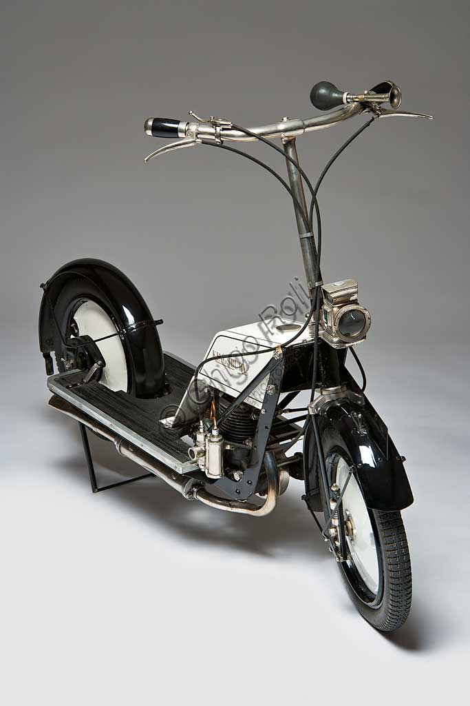 Moto d'epoca Kingsbury Scooter.Marca: Kingsbury Aviation Co.modello: Scooternazione: Regno Unito -Kingsbury, Londonanno: 1918condizioni: restauratocilindrata: 150 ccmotore: monocilindrico a due tempi cambio: Quando venne presentato, questo scooter inglese reclamizzava il disegno che, con motore protetto, ampio silenziatore sotto il pianale, carter della catena avvolgente, avrebbe garantito una assoluta pulizia del conducente. A quei tempi infatti, il problema maggiore per chi viaggiava in scooter, sembrava essere il far ritorno da ogni, sia pur breve, spostamento tutti imbrattati d'olio benzina e polvere della strada. Anche le piccole sospensioni a molla montate direttamente sul mozzo, tentavano di offrire un certo confort.Il motore a due tempi erogava una potenza di 2,5 Hp. Non sappiamo molto altro di questo scooter che evidentemente non ebbe grande diffusione. Oggi se ne conoscono solo tre esemplari superstiti.