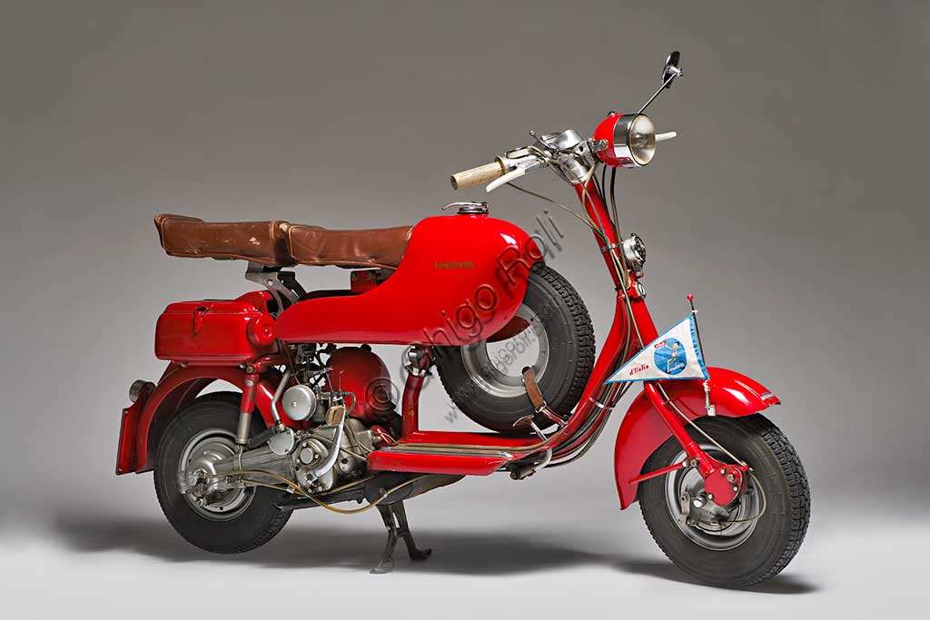 Moto d'epoca Lambretta  D Sport. Scooter.Marca: Innocentimodello: Lambretta D Sportnazione: Italia - Milanoanno: 1954condizioni: restauratacilindrata: 123 cc. (alesaggio e corsa 52 x 58)motore: monocilindrico a due tempicambio: a tre rapporti con comando al manubrioNei suoi primi anni di vita la Lambretta si cimentò anche nelle corse e lo fece con notevoli successi. Già nel 1951, con una Lambretta C, Ernesto Longoni coprì i 1340 chilometri della Milano-Taranto in 17 ore e 26 minuti, ovviamente vincendo nella sua categoria, alla media di 75,9 km/h; era una media  straordinaria se si pensa che la "C" di serie faceva al massimo i 90 km/h. Anche nel '53, Luigi Fumagalli con una "D" Sport del tutto simile a questa, vinse di nuovo la Milano-Taranto. Poi la Innocenti chiuderà definitivamente la stagione delle competizioni, un'attività decisamente lontana dalla filosofia della Lambretta, che pure aveva dimostrato una grandissima affidabilità.