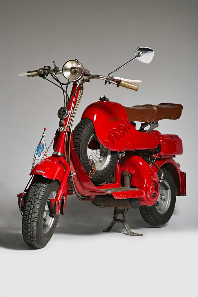 Moto d'epoca Lambretta  D Sport. Scooter.Marca: Innocentimodello: Lambretta D Sportnazione: Italia - Milanoanno: 1954condizioni: restauratacilindrata: 123 cc. (alesaggio e corsa 52 x 58)motore: monocilindrico a due tempicambio: a tre rapporti con comando al manubrioNei suoi primi anni di vita la Lambretta si cimentò anche nelle corse e lo fece con notevoli successi. Già nel 1951, con una Lambretta C, Ernesto Longoni coprì i 1340 chilometri della Milano-Taranto in 17 ore e 26 minuti, ovviamente vincendo nella sua categoria, alla media di 75,9 km/h; era una media  straordinaria se si pensa che la "C" di serie faceva al massimo i 90 km/h. Anche nel '53, Luigi Fumagalli con una "D" Sport del tutto simile a questa, vinse di nuovo la Milano-Taranto. Poi la Innocenti chiuderà definitivamente la stagione delle competizioni, un'attività decisamente lontana dalla filosofia della Lambretta, che pure aveva dimostrato una grandissima affidabilità.