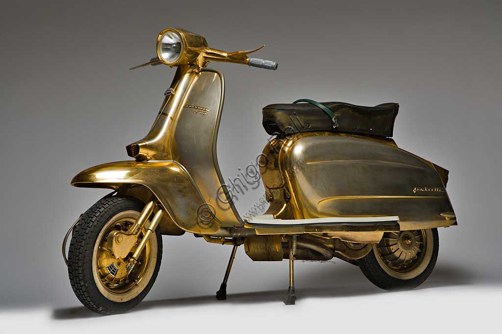 Moto d'epoca Lambretta TV  175. Scooter.Marca: Innocenti modello: Lambretta TV 175 III Serie nazione: Italia - Milanoanno: 1962condizioni: conservatacilindrata: 175 (alesaggio e corsa 62 x 58)motore: monocilindrico a due tempicambio: a quattro rapporti con comando al manubrioProgettata nella seconda metà degli anni '50 e prodotta a partire dal '57 con la prima serie, la Tv fu una delle Lambrette di maggior successo.  La TV Terza Serie introduce, primo tra gli scooter, il più sicuro freno a disco anteriore (che però non si vede, racchiuso come è in una protezione che lo ingloba al mozzo).Questo esemplare, unico al mondo, è interamente placcato in oro in ogni suo componente. Lo ordinò così per sé Jayne Mansfield, dopo essere stata testimonial pubblicitario per il lancio della Lambretta Terza Serie ed essersi innamorata dello stile di questo scooter.  La biondissima attrice morì in un incidente stradale senza averla mai ritirata e questa Lambretta rimase per molti anni in un angolo dei capannoni di Lambrate.