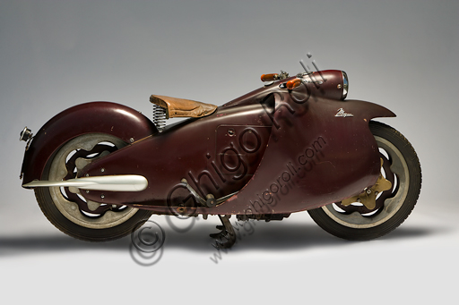 Vintage motorbike Mayor.Brand: Mayorcountry: Italy - Turinyear: 1947conditions: preserveddisplacement: 349.3 cc. (bore and stroke 76 x 77)engine: vertical single cylinder with overhead valvesgearbox: four-speed with pedal controland final shaft transmissionOne of the most futuristic projects in the history of the motorcycle is due to Salvatore Maiorca, (hence the name of the motorcycle), a brilliant engineer well known in Turin. The Mayor, of which this unique prototype survives, built in the Aeritalia workshops of the Fiat group and thought probably for the municipal police. It has load-bearing and enveloping bodywork that integrates the headlight and mudguards, indirect steering, forced air-cooled aeronautical engine, longitudinal crankshaft that extends in the block gearbox and the shaft transmission. But the most innovative feature for which the Mayor will be remembered, even if it did not follow, are the elastic wheels: a steel disc joins the outer rim to the internal hub by means of rubber pads ensuring, at least in theory, the springing of the motorcycle without the need for other suspension.