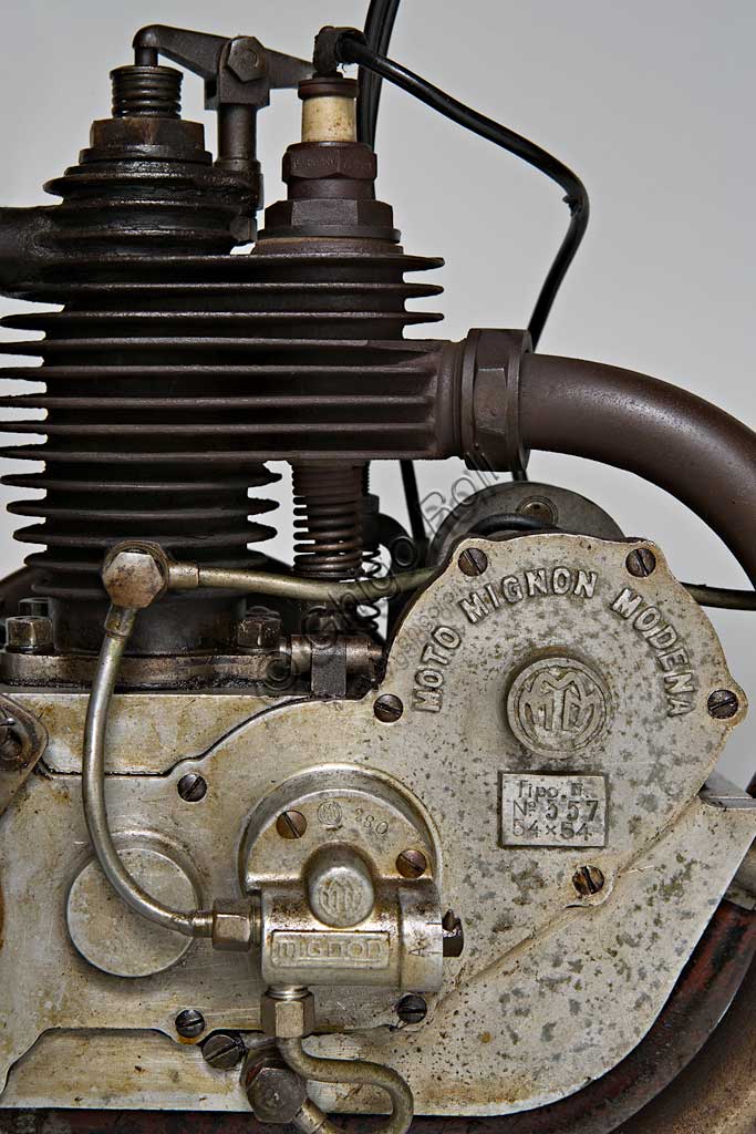 Moto d'epoca Mignon 125 N. Motore.Marca: Moto Mignon Modena (MMM)modello: 125 Tipo Normalenazione: Italia - Modenaanno: 1925condizioni: conservatacilindrata: 123,6 (alesaggio e corsa 54 x 54)motore: monocilindrico a valvole contrapposte: aspirazione in testa, scarico lateralecambio: in blocco a due rapportiVittorio Guerzoni, dopo un tirocinio a Torino nell' industria automobilistica dove, lavorando da operaio, si diploma meccanico, apre la sua officina a Modena nel dopoguerra. Costruisce il primo prototipo della sua bicicletta a motore nel '20, con motore progettato da Armando Caiumi. Più tardi costruirà moto più potenti di 175, 250 e 500 cc, anche nella versione Corsa, alcune delle quali furono utilizzate dalla scuderia Ferrari. Dopo il '33 non compare più il marchio Mignon ma Guerzoni continua a costruire alcune moto con il suo nome (Moto Guerzoni - MG) e, soprattutto, i motori Taurus per conto del Cav. Fabbri di Milano.