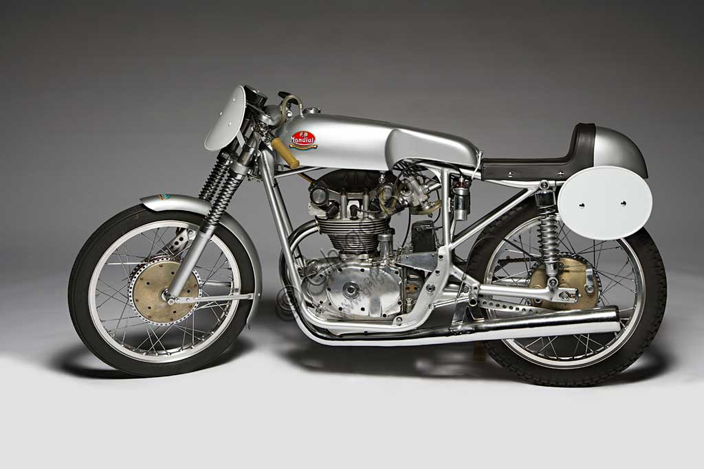 Moto d'epoca Mondial  175 Marca: Mondialmodello: 175nazione: Italia - Bologna e Milanoanno: 1954condizioni: restauratacilindrata: 174,4 (alesaggio e corsa 62 x 57,8)motore: monocilindricocambio: in blocco a cinque rapportiNata nel 1929 per volontà dei conti Boselli di Ancarano (Piacenza), la F.B. Mondial produsse fino alla Seconda Guerra Mondiale solo motocarri per trasporto merci. Ma l'amore per le motociclette che aveva segnato Giuseppe, uno dei fratelli Boselli fin da ragazzo, riemerge nel '46 quando vide la luce una 125 quattro tempi bialbero, molto innovativa per l'epoca, progettata da Alfonso Drusiani. Appena nata la piccola 125 battè il record sul chilometro lanciato e diede inizio a una lunga stagione di successi che vide la Mondial produrre prima solo moto per le corse, poi anche per i privati, ma sempre molto vicine allo spirito agonistico. Questo modello, nato anch'esso per le corse, raggiungeva, in versione carenata, i 181 km/h.