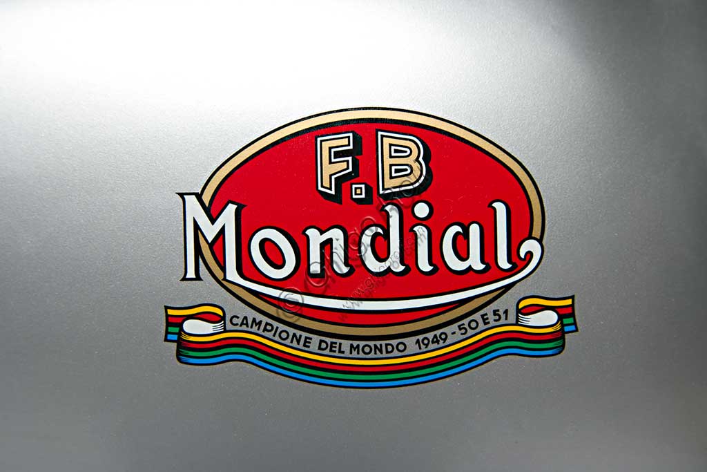 Moto d'epoca Mondial  175. Marchio.Marca: Mondialmodello: 175nazione: Italia - Bologna e Milanoanno: 1954condizioni: restauratacilindrata: 174,4 (alesaggio e corsa 62 x 57,8)motore: monocilindricocambio: in blocco a cinque rapportiNata nel 1929 per volontà dei conti Boselli di Ancarano (Piacenza), la F.B. Mondial produsse fino alla Seconda Guerra Mondiale solo motocarri per trasporto merci. Ma l'amore per le motociclette che aveva segnato Giuseppe, uno dei fratelli Boselli fin da ragazzo, riemerge nel '46 quando vide la luce una 125 quattro tempi bialbero, molto innovativa per l'epoca, progettata da Alfonso Drusiani. Appena nata la piccola 125 battè il record sul chilometro lanciato e diede inizio a una lunga stagione di successi che vide la Mondial produrre prima solo moto per le corse, poi anche per i privati, ma sempre molto vicine allo spirito agonistico. Questo modello, nato anch'esso per le corse, raggiungeva, in versione carenata, i 181 km/h.