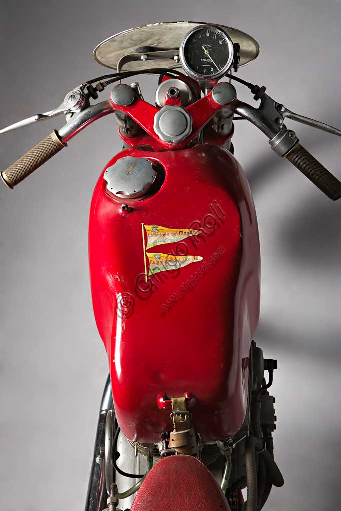 Moto d'epoca MV Agusta 125 Monoalbero CorsaMarca: MV Agustamodello: 125 Monoalbero Corsanazione: Italia - Schiranna (VA)anno: 1954condizioni: conservatacilindrata: 123,5 (alesaggio e corsa 53 x 56)motore: monocilindrico, albero a cammes in testacambio: a quattro rapportiLa storica azienda fondata nel 1907 dal Conte Giovanni Agusta, nota per la produzione aeronautica, iniziò a produrre motociclette con il figlio Domenico solo nel '46, con il nome Meccanica Verghera (MV). Dopo le prime 98, nelle versioni Turismo e Sport, costruisce moto sempre più orientate verso le competizioni; questo esemplare, che toccava i 150 km/h, ne è una delle prime testimonianze.E' appena il caso di ricordare che, la MV con  75 campionati del mondo e 270 Gran Premi vinti, è la marca più vittoriosa della storia del motociclismo. Un record nei record: con Giacomo Agostini, vinse ininterrottamente il campionato del mondo dal 1967 al 1973 sia nella classe 350 che nella 500.