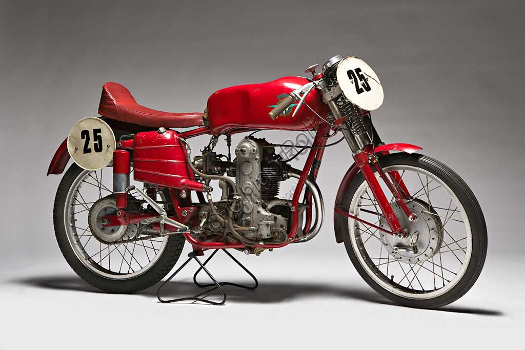 Moto d'epoca MV Agusta 125 Monoalbero CorsaMarca: MV Agustamodello: 125 Monoalbero Corsanazione: Italia - Schiranna (VA)anno: 1954condizioni: conservatacilindrata: 123,5 (alesaggio e corsa 53 x 56)motore: monocilindrico, albero a cammes in testacambio: a quattro rapportiLa storica azienda fondata nel 1907 dal Conte Giovanni Agusta, nota per la produzione aeronautica, iniziò a produrre motociclette con il figlio Domenico solo nel '46, con il nome Meccanica Verghera (MV). Dopo le prime 98, nelle versioni Turismo e Sport, costruisce moto sempre più orientate verso le competizioni; questo esemplare, che toccava i 150 km/h, ne è una delle prime testimonianze.E' appena il caso di ricordare che, la MV con  75 campionati del mondo e 270 Gran Premi vinti, è la marca più vittoriosa della storia del motociclismo. Un record nei record: con Giacomo Agostini, vinse ininterrottamente il campionato del mondo dal 1967 al 1973 sia nella classe 350 che nella 500.