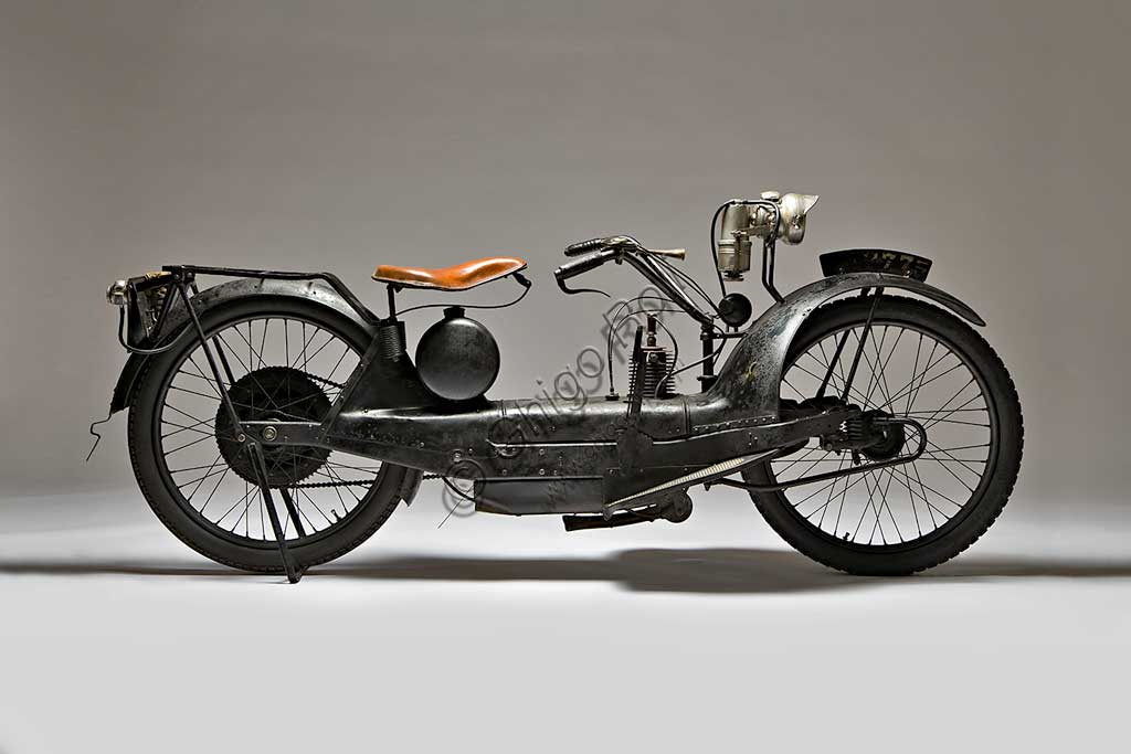 Moto d'epoca NER-A-CAR Model A. Scooter.Marca: Simplex Co. / Neracar Corp.modello: Model Anazione: U.K. - Sheffield / U.S.A. - Syracuse N.Y.  anno: 1923condizioni: restauratacilindrata: 221 (13,5 cubic inch)motore: monocilindrico a due tempicambio: trasmissione continua con variatore a volano comandato da levaGiocando sul proprio nome Carl A. Neracher battezzò Ner-A-Car questa sua creatura unica che stava a metà strada tra una moto e uno scooter e, per la sua comodità, doveva essere near a car, quasi un'automibile. Prodotta a Sheffield per l'Europa (come nel caso di questo esemplare), e a Syracuse negli States, la Ner-A-Car ha una scocca a tunnel in lamiera stampata di tipo automobilistico, molto bassa, che consente anche alle donne di guidarla facilmente e la rende molto manovrabile. Ha caratteristiche ciclistiche e meccaniche assolutamente uniche: lo sterzo è indiretto a giunto sferico collocato al centro del mozzo e comandato da tiranti;  la trasmissione è continua con variatore a volano e disco perpendicolare rivestito di materiale d'aderenza,  il comando a leva lo trasla sul volano variando, con la circonferenza, i giri. Il giornalista di Motorcycle che la recensì all'epoca, scrisse che andava molto bene ma che servivano tre mani per guidarla.