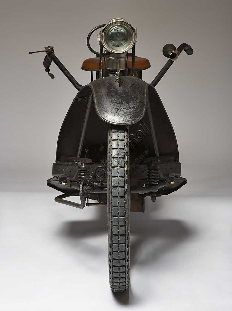 Moto d'epoca NER-A-CAR Model A. Scooter.Marca: Simplex Co. / Neracar Corp.modello: Model Anazione: U.K. - Sheffield / U.S.A. - Syracuse N.Y.  anno: 1923condizioni: restauratacilindrata: 221 (13,5 cubic inch)motore: monocilindrico a due tempicambio: trasmissione continua con variatore a volano comandato da levaGiocando sul proprio nome Carl A. Neracher battezzò Ner-A-Car questa sua creatura unica che stava a metà strada tra una moto e uno scooter e, per la sua comodità, doveva essere near a car, quasi un'automibile. Prodotta a Sheffield per l'Europa (come nel caso di questo esemplare), e a Syracuse negli States, la Ner-A-Car ha una scocca a tunnel in lamiera stampata di tipo automobilistico, molto bassa, che consente anche alle donne di guidarla facilmente e la rende molto manovrabile. Ha caratteristiche ciclistiche e meccaniche assolutamente uniche: lo sterzo è indiretto a giunto sferico collocato al centro del mozzo e comandato da tiranti;  la trasmissione è continua con variatore a volano e disco perpendicolare rivestito di materiale d'aderenza,  il comando a leva lo trasla sul volano variando, con la circonferenza, i giri. Il giornalista di Motorcycle che la recensì all'epoca, scrisse che andava molto bene ma che servivano tre mani per guidarla.