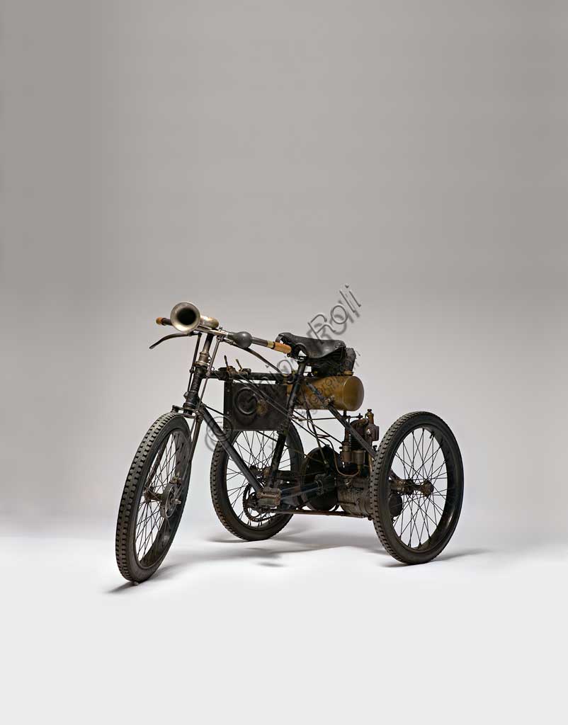 Moto d'epoca Perfecta Triciclo tipo Sport.Marca: Perfecta/ De Dion Boutonmodello: tipo Sportnazione: Italia - Torinoanno: 1898condizioni: restauratocilindrata: 240 ccmotore: Monocilindrico a valvole contrapposteaspirazione automatica in testa, scarico lateralecambio:trasmissione diretta a ingranaggi con differenzialeNell'epoca dei primi pionieri dell'era del motore figura la Perfecta di Bender & Martiny. Ha sede a Nole Canavese e si occupa in un primo tempo dell'assemblaggio di vetture con parti di provenienza francese e tedesca. Poi, dal 1898, inizia la costruzione di tricicli e quadricicli con motorizzazione Gaillardet o, come in questo caso, montando il collaudato monocilindrico De Dion-Bouton. In questi stessi anni, in Italia, tricicli simili e con la stessa motorizzazione De Dion-Bouton vengono fabbricati da Bianchi, Prinetti e Stucchi e altri. La ditta, dal 1903, produrrà solo automobili con il prestigioso marchio Invicta. Questo esemplare, che partecipò alla Parigi-Bordeaux, monta un carburatore a superficie, freno anteriore a nastro, e raggiunge ancor oggi i 45 km/h.