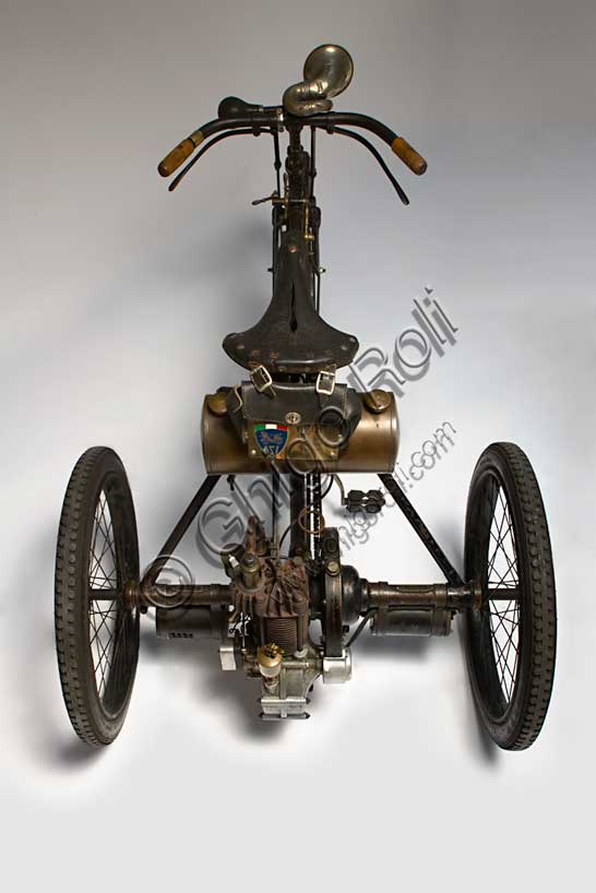 Vintage motorcycle “Perfecta Triciclo tipo Sport”.Brand: Perfecta / De Dion Boutonmodel: Sport typecountry: Italy - Turinyear: 1898condition: restoreddisplacement: 240 ccengine: Single-cylinder with opposed valves with automatic overhead intake, side exhaustgearbox: direct transmission with gears with differentialIn the era of the first pioneers of the engine era, there is Perfecta by Bender & Martiny. It is based in Nole Canavese and initially deals with the assembly of cars with parts of French and German origin. Then, from 1898, it begins the construction of tricycles and quadricycles with Gaillardet engines or, as in this case, mounting the proven single-cylinder De Dion-Bouton. In these same years, in Italy, similar tricycles and with the same De Dion-Bouton engines are manufactured by Bianchi, Prinetti and Stucchi and others.