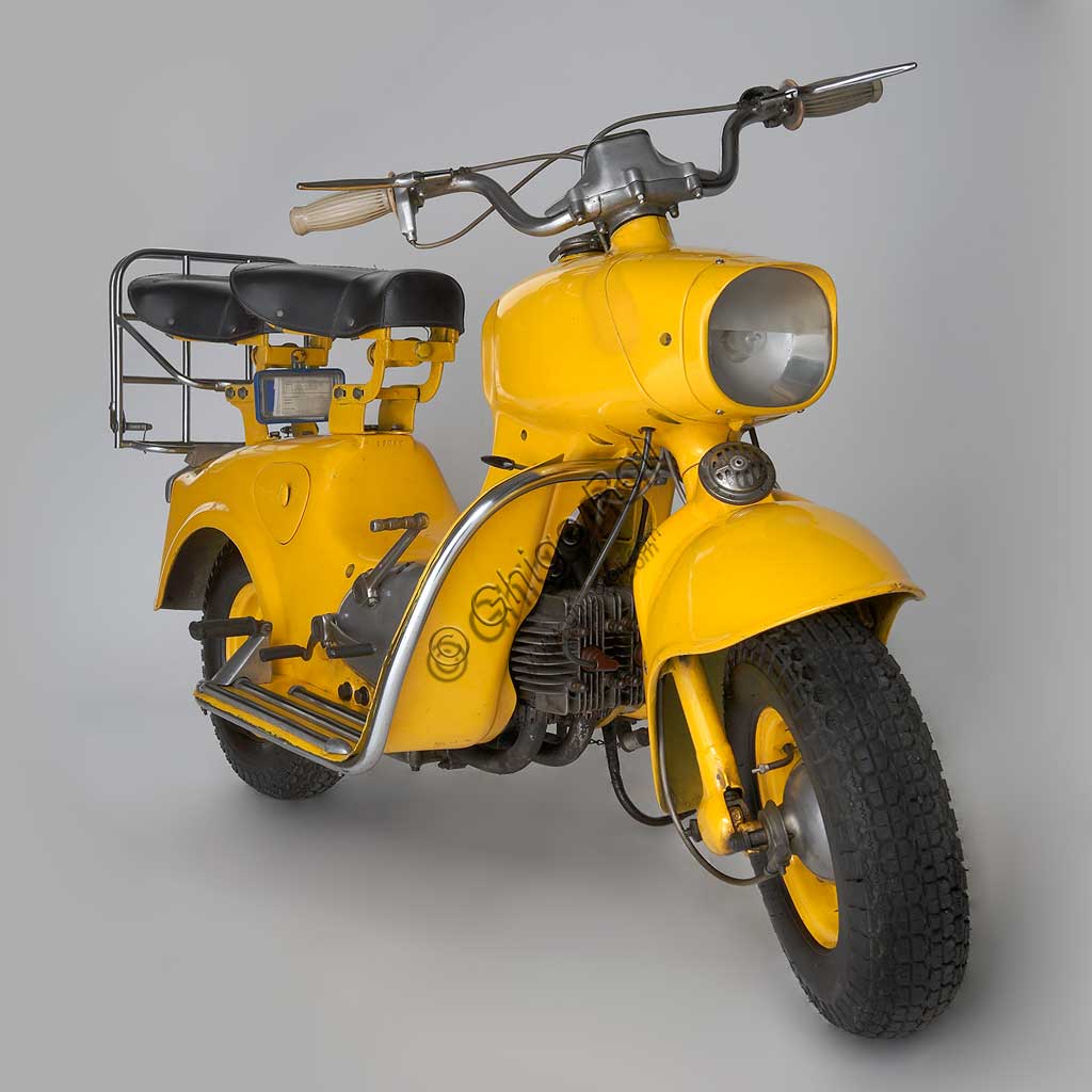 Moto d'epoca Rumi Formichino. Scooter.Marca: Fonderie Officine Rumimodello: Formichinonazione: Italia - Bergamoanno: 1955 - 6condizioni: restauratocilindrata: 124,6 (alesaggio e corsa 42 x 45)motore: bicilindrico orizzontalecambio: in blocco a quattro rapportiSull'onda del successo di Vespa e Lambretta, la Rumi sentì il bisogno di produrre il proprio scooter. La mitologia degli estimatori della casa vuole che la forma assolutamente unica del Formichino sia stata plasmata direttamente nella creta da scultore da Donnino Rumi dopo averne fissato il motore su due cavalletti. Di fatto la carrozzeria portante di questo gigantesco insetto meccanico è fusa in lega d'alluminio in due sole parti: quella anteriore incorpora serbatoio, forcella e faro, quella posteriore tutto il resto. Ebbe qualche successo anche nelle competizioni, vincendo il ventinovesimo Bol d'Or, al quale fece seguito una piccola tiratura di Formichini con questo nome. Dal 1958 la produzione fu ceduta in licenza alla belga Sarolea.