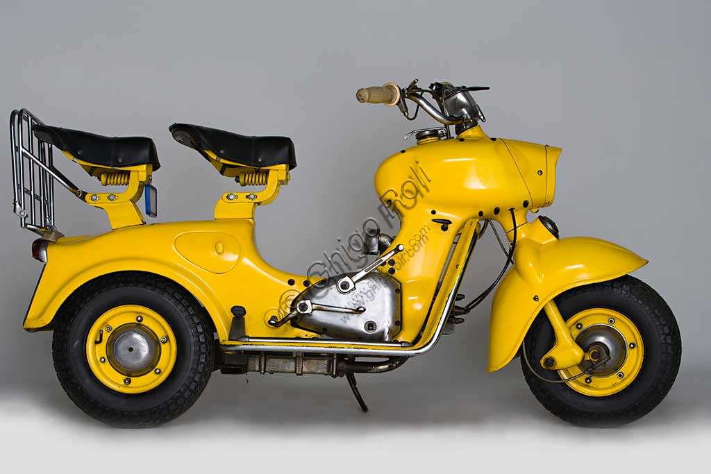 Moto d'epoca Rumi Formichino. Scooter.Marca: Fonderie Officine Rumimodello: Formichinonazione: Italia - Bergamoanno: 1955 - 6condizioni: restauratocilindrata: 124,6 (alesaggio e corsa 42 x 45)motore: bicilindrico orizzontalecambio: in blocco a quattro rapportiSull'onda del successo di Vespa e Lambretta, la Rumi sentì il bisogno di produrre il proprio scooter. La mitologia degli estimatori della casa vuole che la forma assolutamente unica del Formichino sia stata plasmata direttamente nella creta da scultore da Donnino Rumi dopo averne fissato il motore su due cavalletti. Di fatto la carrozzeria portante di questo gigantesco insetto meccanico è fusa in lega d'alluminio in due sole parti: quella anteriore incorpora serbatoio, forcella e faro, quella posteriore tutto il resto. Ebbe qualche successo anche nelle competizioni, vincendo il ventinovesimo Bol d'Or, al quale fece seguito una piccola tiratura di Formichini con questo nome. Dal 1958 la produzione fu ceduta in licenza alla belga Sarolea.