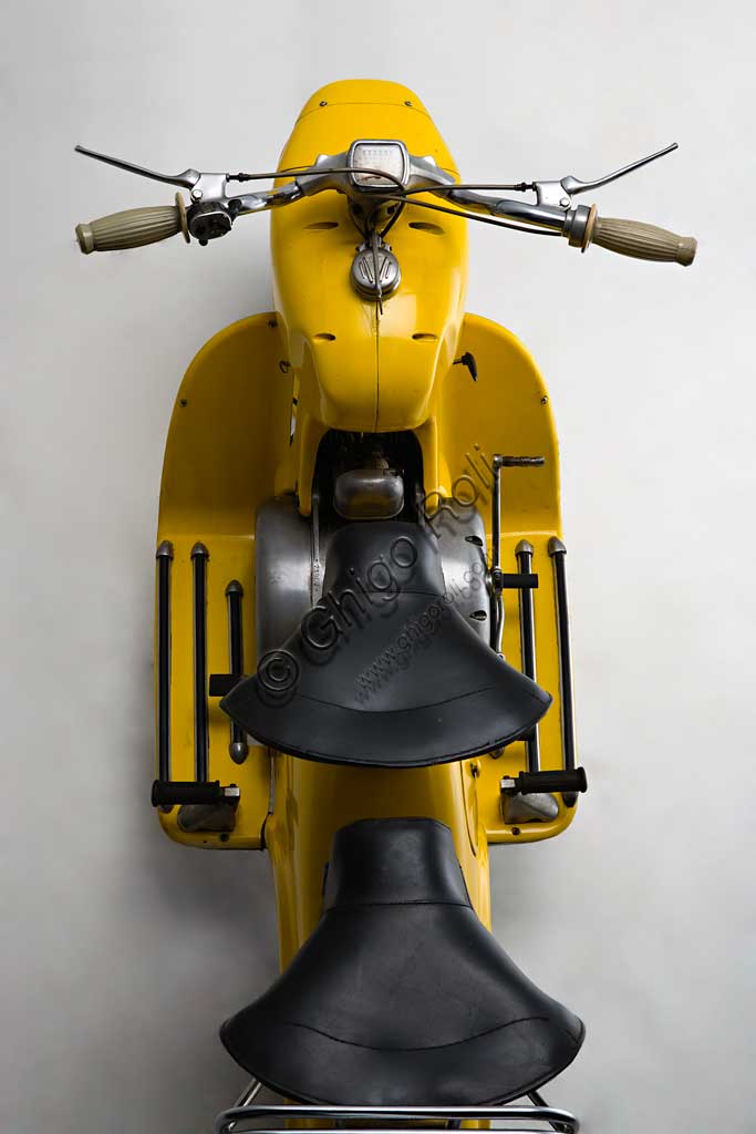 Moto d'epoca Rumi Formichino. Scooter.Marca: Fonderie Officine Rumimodello: Formichinonazione: Italia - Bergamoanno: 1955 - 6condizioni: restauratocilindrata: 124,6 (alesaggio e corsa 42 x 45)motore: bicilindrico orizzontalecambio: in blocco a quattro rapportiSull'onda del successo di Vespa e Lambretta, la Rumi sentì il bisogno di produrre il proprio scooter. La mitologia degli estimatori della casa vuole che la forma assolutamente unica del Formichino sia stata plasmata direttamente nella creta da scultore da Donnino Rumi dopo averne fissato il motore su due cavalletti. Di fatto la carrozzeria portante di questo gigantesco insetto meccanico è fusa in lega d'alluminio in due sole parti: quella anteriore incorpora serbatoio, forcella e faro, quella posteriore tutto il resto. Ebbe qualche successo anche nelle competizioni, vincendo il ventinovesimo Bol d'Or, al quale fece seguito una piccola tiratura di Formichini con questo nome. Dal 1958 la produzione fu ceduta in licenza alla belga Sarolea.