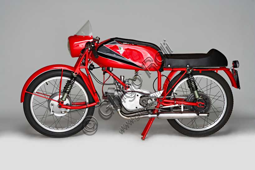 Moto d'epoca “Rumi Junior 125”Marca: Fonderie Officine Rumimodello: Junior 125nazione: Italia - Bergamoanno: 1956condizioni: restauratacilindrata: 124,6 (alesaggio e corsa 42 x 45)motore: bicilindrico orizzontale due tempicambio: in blocco a quattro rapportiDonnino Rumi subentra al padre nella fonderia per bronzo da questi creata. Durante la Seconda Guerra Mondiale rifiuta di convertire la produzione a scopi bellici e diventa partigiano latitante. Nel dopoguerra, alla domanda di mezzi di trasporto economici, risponde affiancando la produzione di motoleggere a quella già avviata di macchine tessili e per pastifici. Con l'aiuto dell'amico progettista nautico Pietro Vassena, nel 1949 è in grado di presentare al salone di Milano la prima, innovativa, motocicletta Rumi.La Junior deriva dalla "Bicarburatore" monta una forcella Earles, ed è fin dall'inizio destinata alle corse. Viene venduta a corridori privati sia italiani che stranieri e, grazie alla sua agilità, riscuote grande successo.