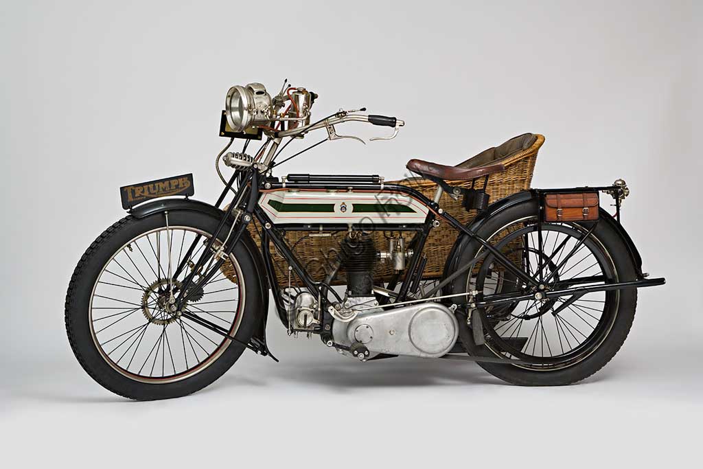 Moto d'epoca Triumph H SideMarca: Triumphmodello: H Sidenazione: Regno Unito - Coventryanno: 1918condizioni: restauratocilindrata: 550,1 (alesaggio e corsa 85 x 97)motore: quattro tempi a valvole lateralicambio: Sturmey Archer a tre rapportitrasmissione finale a cinghiaDopo aver prodotto biciclette per alcuni anni, nel 1902 la Triumph, casa fondata da tre immigrati tedeschi, costruisce la sua prima bicicletta a motore con motorizzazione Minerva. A questa fanno seguito alcuni modelli sempre motorizzati da altri, fino al  1905 quando inizia la produzione della prima motocicletta costruita interamente in casa Triumph.  Nel 1915 esce il modello H, di cui qui presentiamo un elegante esemplare con motocarrozzetta. Monta un motore disegnato da Mauritz Schülte, uno dei tre soci, ed è concepita per l'esercito. Si rivela però talmente affidabile e piacevole da condurre che, nel dopoguerra, conoscerà una grande diffusione anche tra i privati, dando inizio a quel successo che farà della Triumph una delle più prestigiose marche britanniche.