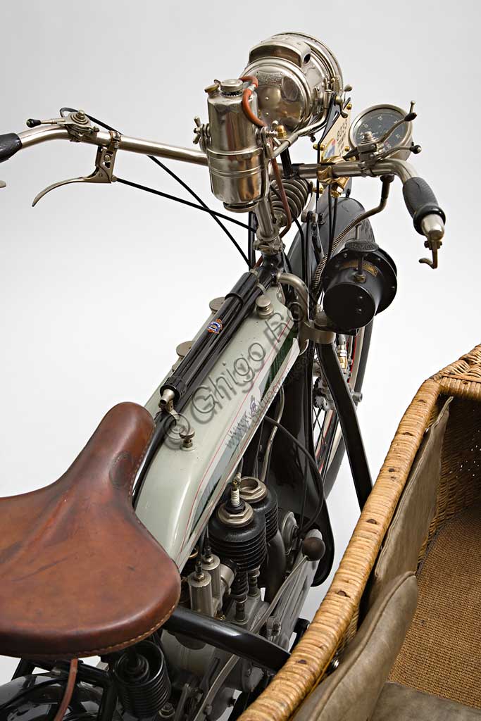 Moto d'epoca Triumph H SideMarca: Triumphmodello: H Sidenazione: Regno Unito - Coventryanno: 1918condizioni: restauratocilindrata: 550,1 (alesaggio e corsa 85 x 97)motore: quattro tempi a valvole lateralicambio: Sturmey Archer a tre rapportitrasmissione finale a cinghiaDopo aver prodotto biciclette per alcuni anni, nel 1902 la Triumph, casa fondata da tre immigrati tedeschi, costruisce la sua prima bicicletta a motore con motorizzazione Minerva. A questa fanno seguito alcuni modelli sempre motorizzati da altri, fino al  1905 quando inizia la produzione della prima motocicletta costruita interamente in casa Triumph.  Nel 1915 esce il modello H, di cui qui presentiamo un elegante esemplare con motocarrozzetta. Monta un motore disegnato da Mauritz Schülte, uno dei tre soci, ed è concepita per l'esercito. Si rivela però talmente affidabile e piacevole da condurre che, nel dopoguerra, conoscerà una grande diffusione anche tra i privati, dando inizio a quel successo che farà della Triumph una delle più prestigiose marche britanniche.