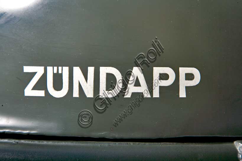 Moto d'epoca “Zündapp KS”Marca: Zündappmodello: KSnazione: Germaniaanno: 1942condizioni: restauratacilindrata: 750 cc.motore: bicilindrico boxercambio: a 4 rapporti e retromarcia, trasmissione ad albero, due ruote posteriori motrici, con differenziale ripartitore e bloccabileFondata nel '17 dalla Friederich Krupp AG e dall'ing. Fritz Neumeyer come fabbrica di  macchine utensili (Zunder und Apparatebau GmbH) la Zündapp viene presto convertita alla sola produzione di motociclette. Dal 1940 la produzione si concentra sulle moto militari per la Wehrmacht. Di questa produzione il sidecar qui raffigurato è il modello più prodotto con 18.000 esemplari costruiti. Il telaio (rigido) fu disegnato da Ferdinand Porsche. Ruote e freni sono di produzione BMW. Anche il carrozzino, fornito da ditte esterne, è uguale a quello BMW per fini di unificazione richiesti dall'esercito.