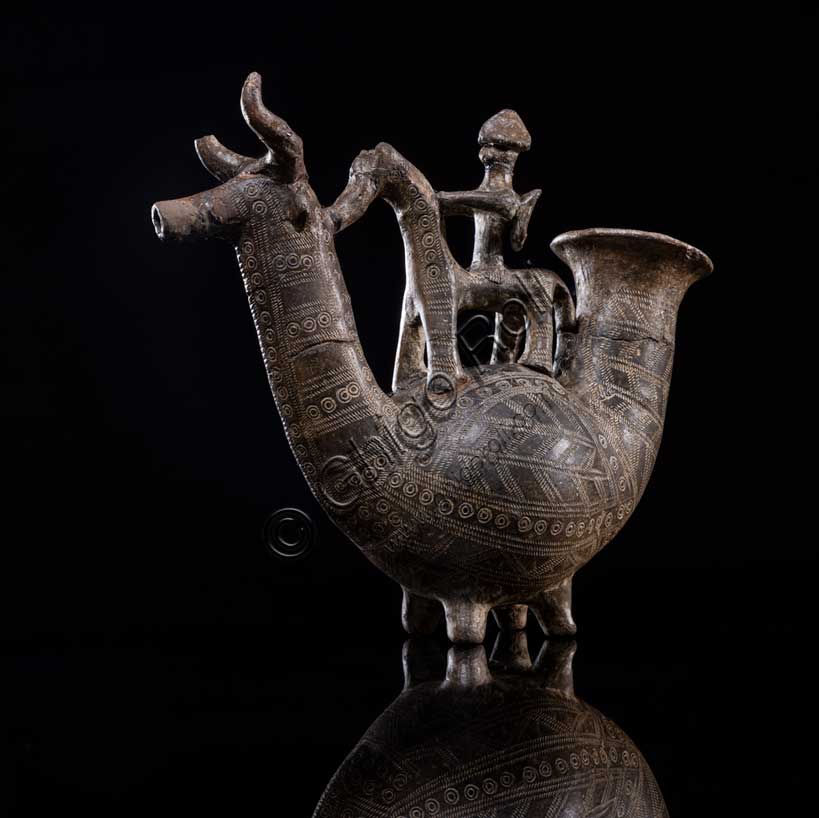 Museo Civico Archeologico di Bologna: “Askos Benacci”; Questo vaso, è uno degli oggetti più noti del museo.Proviene da una tomba del sepolcreto Benacci, dove fu rinvenuto nel 1875. Questo “askòs”, parola che in greco significa otre, è un vaso in terracotta realizzato a forma di animale, con il corpo panciuto, il collo lungo e la testa di toro dalle corna ricurve. Il vaso era utilizzato come contenitore di liquidi pregiati, introdotti attraverso l’apertura della parte posteriore e versati dal foro che l’animale ha sul muso. Il manico ha la forma di un cavallo montato da un cavaliere con lo scudo sulle spalle e l’elmo in testa.L'askos è un documento straordinario anche perchè documenta l’uso di armi difensive, raramente trovate nei corredi funerari bolognesi di epoca villanoviana.L’oggetto, datato tra la fine dell’VIII  e gli inizi del VII secolo a.C., ha una decorazione raffinata, eseguita sull’argilla cruda, prima della cottura. Le due ruote in terracotta, trovate insieme al vaso, potrebbero appartenere ad un carretto su cui era originariamente collocato.La figura del cavaliere indica l’importanza del defunto, mentre l’animale fantastico allude probabilmente al viaggio nell’aldilà. Questo oggetto era indubbiamente carico di significati religiosi e sociali: l’iconografia del cavaliere ribadiva il ruolo eminente del defunto all’interno della comunità.Provenienza: Bologna. Necropoli Benacci, tomba 525Datazione: fine VIII secolo a.C.Inv. 12791