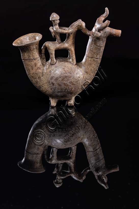 Museo Civico Archeologico di Bologna: “Askos Benacci”; Questo vaso, è uno degli oggetti più noti del museo.Proviene da una tomba del sepolcreto Benacci, dove fu rinvenuto nel 1875. Questo “askòs”, parola che in greco significa otre, è un vaso in terracotta realizzato a forma di animale, con il corpo panciuto, il collo lungo e la testa di toro dalle corna ricurve. Il vaso era utilizzato come contenitore di liquidi pregiati, introdotti attraverso l’apertura della parte posteriore e versati dal foro che l’animale ha sul muso. Il manico ha la forma di un cavallo montato da un cavaliere con lo scudo sulle spalle e l’elmo in testa.L'askos è un documento straordinario anche perchè documenta l’uso di armi difensive, raramente trovate nei corredi funerari bolognesi di epoca villanoviana.L’oggetto, datato tra la fine dell’VIII  e gli inizi del VII secolo a.C., ha una decorazione raffinata, eseguita sull’argilla cruda, prima della cottura. Le due ruote in terracotta, trovate insieme al vaso, potrebbero appartenere ad un carretto su cui era originariamente collocato.La figura del cavaliere indica l’importanza del defunto, mentre l’animale fantastico allude probabilmente al viaggio nell’aldilà. Questo oggetto era indubbiamente carico di significati religiosi e sociali: l’iconografia del cavaliere ribadiva il ruolo eminente del defunto all’interno della comunità.Provenienza: Bologna. Necropoli Benacci, tomba 525Datazione: fine VIII secolo a.C.Inv. 12791