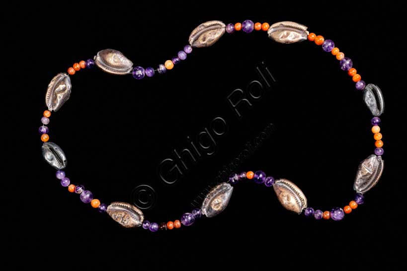 Museo Civico Archeologico di Bologna: collana con cipree, ametista, corniola e argento.Inventario EG 3077Ornamento personale – Medio Regno: XII dinastia (1938-1759 a.C.) Lo splendido gioiello è composto da una serie di perline in corniola e in ametista, alternate a conchiglie cipree in argento lavorate a sbalzo, che ne rappresentano l’elemento caratterizzante. Grazie al confronto con esemplari analoghi rinvenuti in contesti funerari a el-Lisht, Dahshur e Tebe ovest, il monile è databile con sicurezza alla XII dinastia (1938-1759 a.C.). Considerato dalla stragrande maggioranza degli studiosi una collana, questo raro gioiello non è escluso potesse essere usato quale cintura da indossare sui fianchi, non solo per esaltare l’armoniosa nudità di un giovane corpo femminile, ma anche per propiziarne una sicura fertilità, evocata dalle conchiglie cipree che ne sono un simbolo tradizionale. 