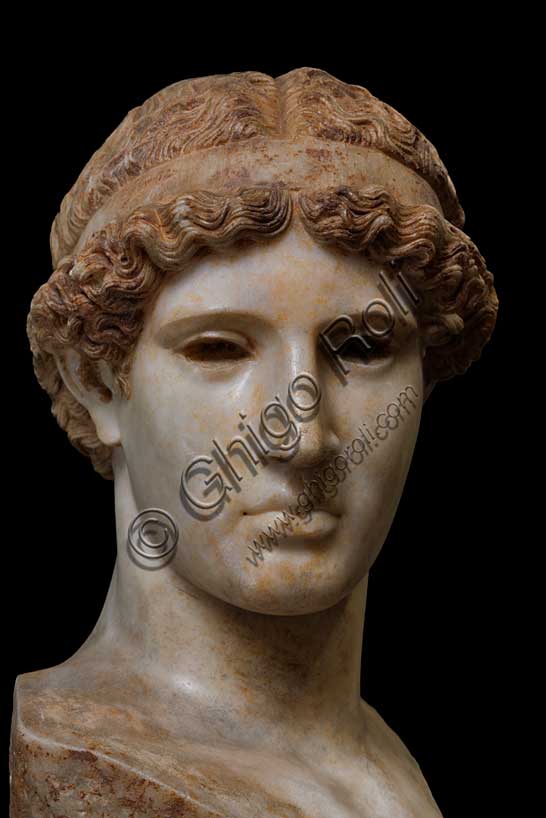 Museo Civico Archeologico di Bologna, collezione greca, sala V: l’Atena Lemnia.Inv. G_1061Capolavoro della Collezione Palagi è la testa di Atena in marmo pentelico, copia d’epoca romana della perduta scultura bronzea a figura intera della dea, commissionata a Fidia, tra il 451 e il 447 a.C., da un gruppo di cittadini ateniesi in procinto di fondare una colonia sull'isola egea di Lemnos.La statua, detta per questo motivo “Lemnia”, fu posta sull’Acropoli di Atene con la funzione di ex-voto, per ottenere la protezione della dea, "patrona" della città, durante la creazione della nuova colonia.La grande novità della scultura fu la scelta da parte di Fidia di raffigurare Atena, solitamente presentata in armi e pronta al combattimento, in atteggiamento pacifico, stante, vestita di tunica e mantello, appoggiata alla lancia e con l'elmo nella mano destra. L'opera non è giunta fino a noi: è tuttavia possibile ricostruirne l'aspetto grazie ad alcune repliche di età romana, che riproducono soprattutto la testa della dea.Tra queste, la migliore per accuratezza e fedeltà all'originale è certamente questa testa, attribuita ad uno scultore greco attivo in età augustea (fine del I sec. a.C.- inizi del I sec. d.C.). L'autore è infatti riuscito felicemente a riprodurre la concezione e l'idea dell'opera originale, traducendole in un materiale, il marmo pentelico, a lui certamente più congeniale del bronzo della statua fidiaca.