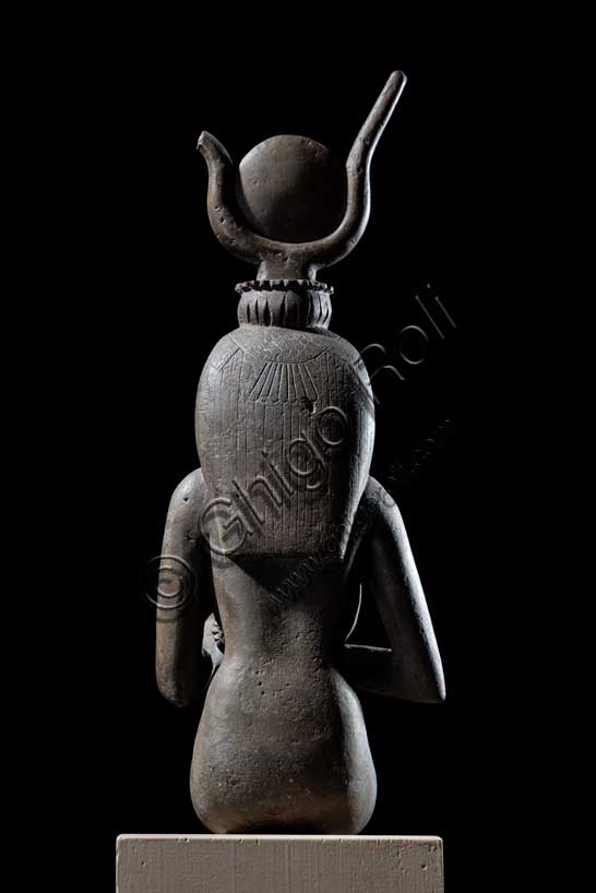 Museo Civico Archeologico di Bologna: Isi (Iside) seduta in trono.Statuetta di Epoca Tarda: XXVI-XXX dinastia (664-342 a.C.). Bronzo con agemina in oro.Inventario EG 248/9.Fra tutte le divinità femminili del pantheon egiziano Isi è la dea per eccellenza, la più conosciuta, “la grande di magia”, soprattutto durante l’Antico Regno (2705-2225 a.C.), quando il suo nome e la sua immagine compaiono raramente sugli edifici religiosi e nei luoghi di culto domestico. Introdotta con un ruolo da protagonista nella leggenda di Osiri, forse attorno al 2500 a.C., le caratteristiche di grande maga si affiancano ad altre più umane, che permettono al suo culto di sopravvivere all'Egitto faraonico, diffondendosi dal VI secolo a.C. in tutto il bacino del Mediterraneo. Isi si identifica così con la fedele compagna del dio Osiri, esperta nell'arte di assecondarlo, di preparane le esequie, di perpetuarne il culto dopo la morte, così come con il prototipo ideale della donna egiziana che veglia sul proprio figlio Horo, erede al trono di Osiri. La dea, raffigurata in questo bronzetto nel suo ruolo di madre premurosa, siede in trono e porge il seno al figlio Horo, ora scomparso. Alla semplicità della veste, una tunica aderente che esalta le linee sinuose del corpo femminile, si contrappongono la ricchezza degli occhi in agemina, la ieraticità della corona hathorica dal tipico disco solare tra corna bovine a lira e il volume dell’acconciatura a tre bande di capelli, sormontata dalla spoglia di avvoltoio. 