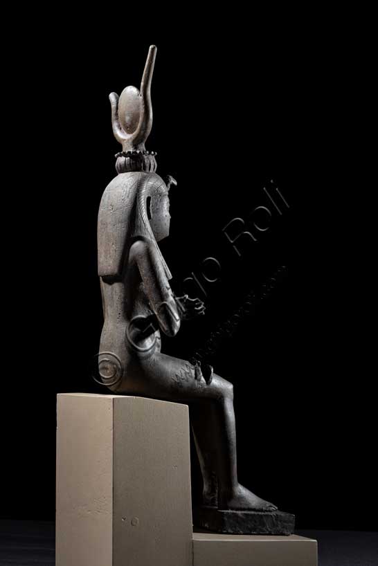 Museo Civico Archeologico di Bologna: Isi (Iside) seduta in trono.Statuetta di Epoca Tarda: XXVI-XXX dinastia (664-342 a.C.). Bronzo con agemina in oro.Inventario EG 248/9.Fra tutte le divinità femminili del pantheon egiziano Isi è la dea per eccellenza, la più conosciuta, “la grande di magia”, soprattutto durante l’Antico Regno (2705-2225 a.C.), quando il suo nome e la sua immagine compaiono raramente sugli edifici religiosi e nei luoghi di culto domestico. Introdotta con un ruolo da protagonista nella leggenda di Osiri, forse attorno al 2500 a.C., le caratteristiche di grande maga si affiancano ad altre più umane, che permettono al suo culto di sopravvivere all'Egitto faraonico, diffondendosi dal VI secolo a.C. in tutto il bacino del Mediterraneo. Isi si identifica così con la fedele compagna del dio Osiri, esperta nell'arte di assecondarlo, di preparane le esequie, di perpetuarne il culto dopo la morte, così come con il prototipo ideale della donna egiziana che veglia sul proprio figlio Horo, erede al trono di Osiri. La dea, raffigurata in questo bronzetto nel suo ruolo di madre premurosa, siede in trono e porge il seno al figlio Horo, ora scomparso. Alla semplicità della veste, una tunica aderente che esalta le linee sinuose del corpo femminile, si contrappongono la ricchezza degli occhi in agemina, la ieraticità della corona hathorica dal tipico disco solare tra corna bovine a lira e il volume dell’acconciatura a tre bande di capelli, sormontata dalla spoglia di avvoltoio. 