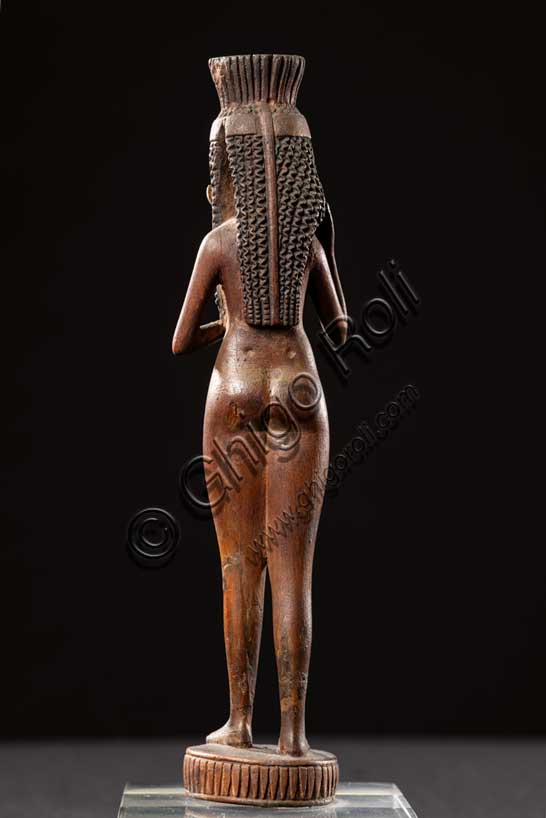 Museo Civico Archeologico di Bologna:  manico di specchio in legno e avorio; Nuovo Regno, fine XVIII - inizi XIX dinastia (1539-1190 a.C.).Inv. EG 1859.Il corpo aggraziato e sensuale di questa fanciulla serviva da manico per uno specchio di metallo, uno degli oggetti da toilette più ambiti dalle signore egiziane facoltose. Un disco in bronzo o in argento, ora scomparso, era fissato alla testa della statuetta. I lunghi riccioli, trattenuti da una fascia che si annoda dietro la testa, e i grandi orecchini in avorio attirano inizialmente sul volto l’attenzione di chi guarda, ma il gesto noncurante con il quale la fanciulla sposta una ciocca di capelli dietro la spalla destra, stringendo al petto un uccellino dalle ali dischiuse, mentre avanza in modo quasi impercettibile la gamba sinistra e divarica un poco i piedi, induce a percorrere l’intera nudità del corpo, caratterizzato da delicata prosperosità e vitale tensione. Era forse così, eternamente giovane, che la proprietaria dello specchio avrebbe desiderato scoprirsi ogni mattina, nell’utilizzarlo per la cura e la cosmesi del proprio corpo.