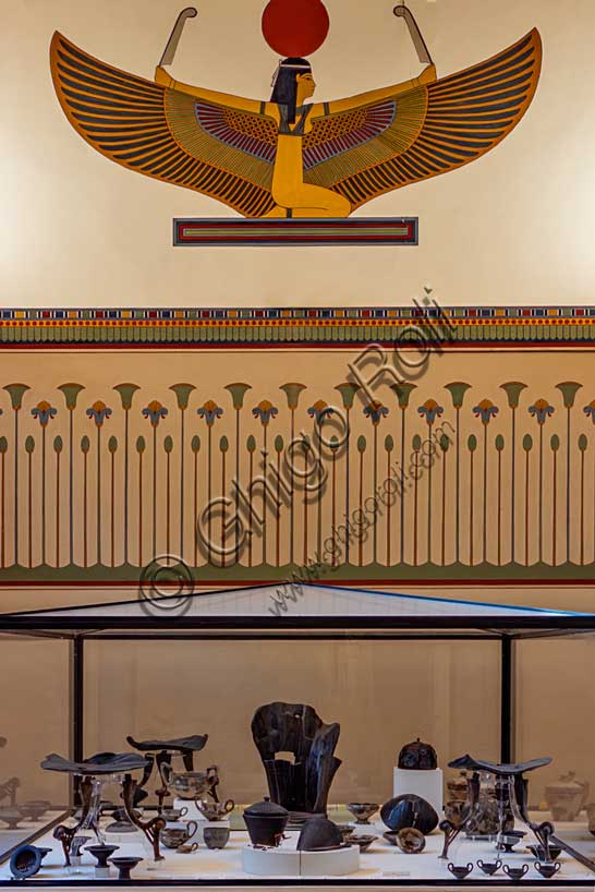 Museo Civico Archeologico di Bologna, sala III: l’allestimento del corredo della tomba 85 dalla necropoli Lippi di Verucchio, uno dei centri Etruschi di maggiore importanza della regione.Tra i materiali di corredo (deposti assieme alle ceneri di un ricco aristocratico) spicca l'imponente trono in legno, decorato ad intaglio, databile al VII secolo a.C., con poggiapiedi. E' il segno più evidente che il defunto avesse rango altissimo.Oltre al trono si segnalano, sempre appartenenti allo stesso corredo, i tre tavolini che ospitavano il vasellame in ceramica contenente le offerte di cibo per il defunto. Tra i cibi è ancora possibile riconoscere uva, nocciole, carne e pesce. A lato del trono vi è un grande elmo in bronzo e vimini, mentre una fibula in bronzo rivestita di preziosa ambra apparteneva all'ornanento personale del defunto.