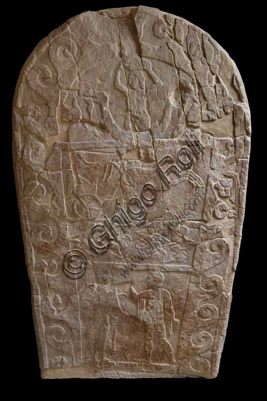 Museo Civico Archeologico di Bologna: Stele funeraria etrusca decorata su quattro registri. Questa stele di dimensioni monumentali, è decorata a bassorilievo su entrambi i lati.ll tema del passaggio del defunto dalla vita alla morte è descritto mediante due scene diverse, in cui compare sempre un demone alato, che, su un lato, “rapisce” il defunto portandolo per mano nell’Aldilà, sull’altro lo guida verso l'oltretomba su una biga trainata da cavalli alati.Questa seconda raffigurazione si inserisce in una delle tre fasce in cui è suddiviso uno dei lati della stele; nelle altre due fasce vi sono, in basso, una rappresentazione di giochi funebri, con un cavaliere etrusco armato che affronta un guerriero nudo con spada e scudo; in alto la lotta tra un serpente ed un ippocampo, animali fantastici che alludono al mondo ultraterreno.Provenienza: Bologna, necropoli della Certosa, tomba 89.Numero di inventario: Ducati 169