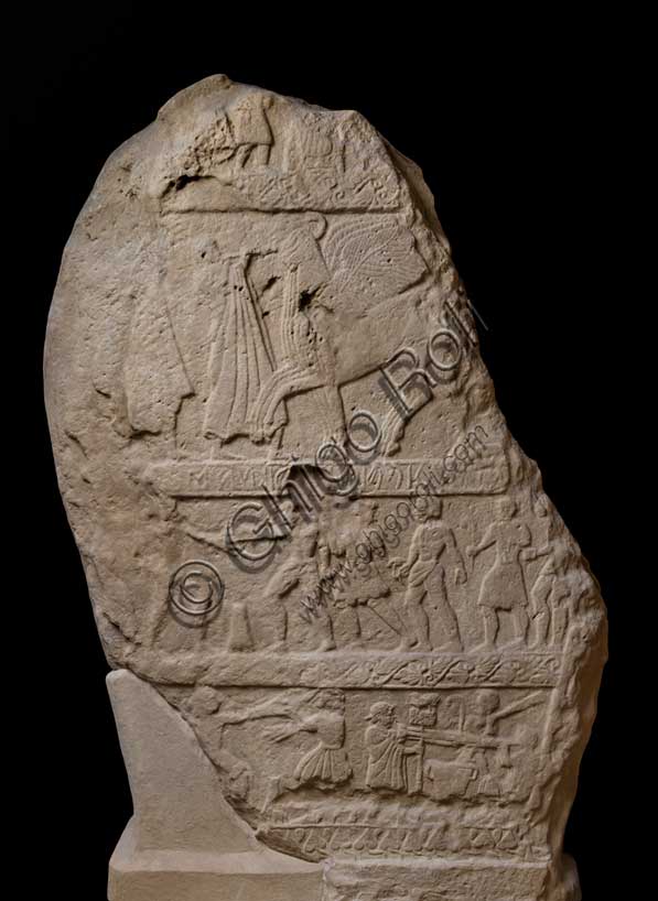 Museo Civico Archeologico di Bologna: Stele funeraria etrusca proveniente dal sepolcreto dei Giardini Margherita. È decorata su entrambi i lati. L’iscrizione [mi] suthi veluś [k]aiknaś, riportata a rilievo, è tradotta come “io sono la tomba di Vel Kaikna”. Il lato A è diviso in quattro zone, delimitate tra loro da quattro grossi listelli, racchiuse da una cornice ora poco leggibile. Si notano il viaggio verso l’aldilà del defunto su una quadriga trainata da cavalli alati e scene di giochi atletici. Il listello più basso, che separa la zona figurata dalla base per l’infissione è decorato da foglie d’edera alternate ad elementi ovoidali. Ultimi decenni del V secolo a.C.Inventario: Ducati 010