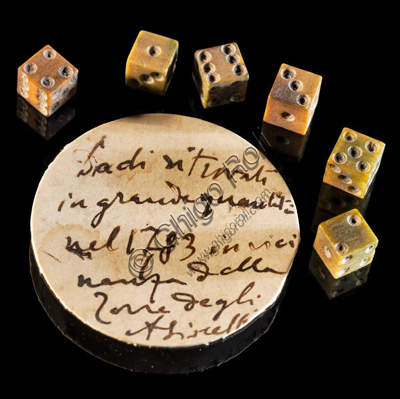 Museo Civico Archeologico di Bologna:minuscoli dadi da gioco, provenienti da sotto la Torre degli Asinelli.Il cartellino dell’epoca riporta: “Dadi ritrovati nel 1783 in vicinanza della Torre degli Asinelli”.Inv.  20096
