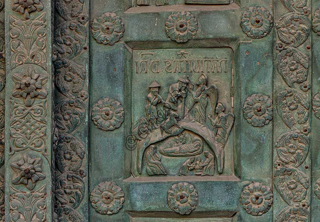 Duomo di Monreale, Porta di Bonanno Pisano (1185-6): formella bronzea con "Natività di Gesù" (scena dal Nuovo Testamento).La porta è firmata: "Bonanno civis pisanus". Iconograficamente nei cinque ordini inferiori vi sono scene del Vecchio Testamento, sette dedicate alla storia di Adamo ed Eva, e altre sei ad altrettante coppie di profeti mentre nei cinque superiori scene del Nuovo, al sommo Cristo e Maria nella gloria del Paradiso.