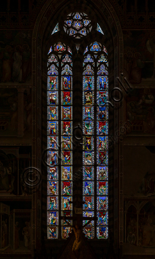  Orvieto,  Basilica Cathedral of Santa Maria Assunta (or Duomo), the interior, apse area: the window made by Giovanni di Bonino in 1328-1334. The forty-four panels of the Gothic window depict the life of Mary and Christ with the bust of the blessing Redeemer surrounded by the symbols of the Evangelists and surmounted by the mystic Cherub. The single episodes of the stories, painted on a blue background within architectural schemes, are interspersed with the figures of the Prophets, represented with landscape notations on a red background.