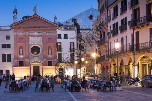   Padua, Piazza dei Signori or Piazza della Signoria: night view with people sitting at bar tables. In the background, the Church of St. Clemente. You can also distinguish a partial view of Palazzo della Ragione.